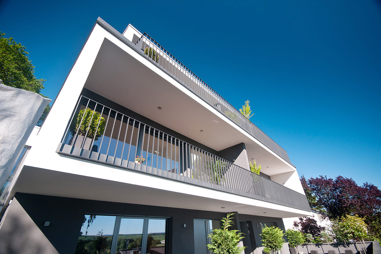 Moderner mehrstöckiger Wohnbau mit großen Balkonen und Metallgeländern unter klarem blauem Himmel